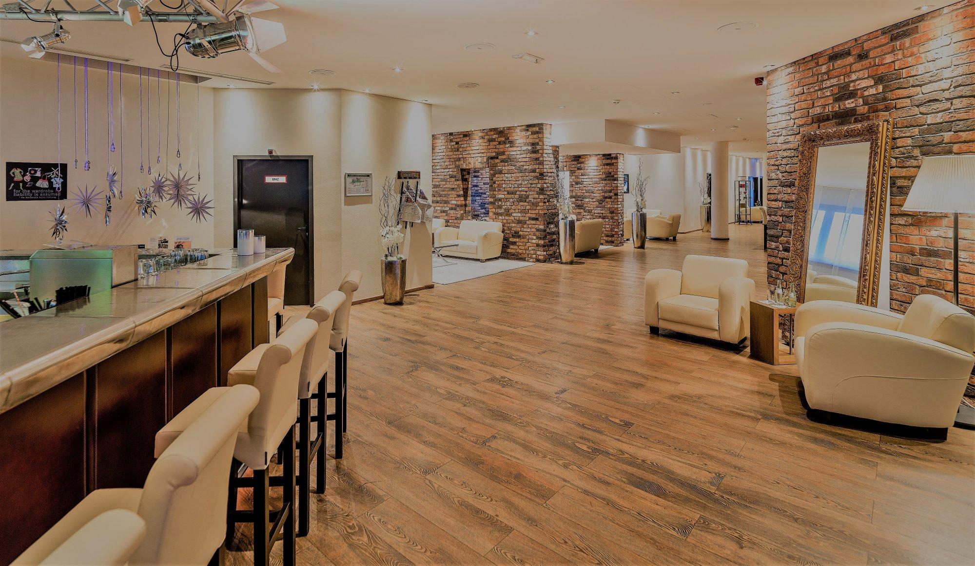 Hell erleuchtete Lounge und Hotelbar mit hellen Sofas und Backsteinwänden