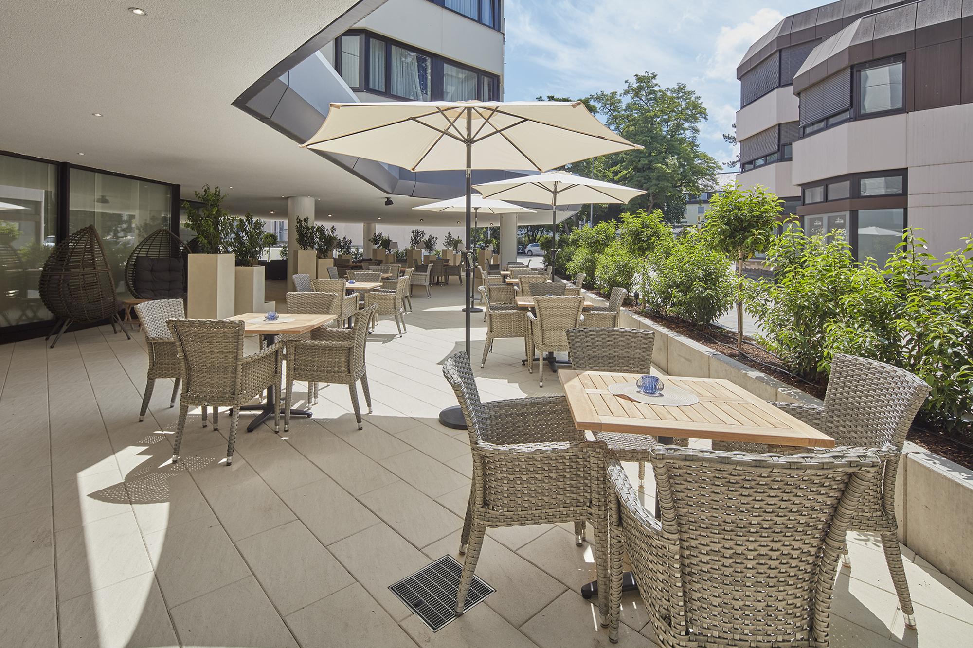 Sonnige Terrasse mit Sonnenschirmen und einer großen Anzahl von Tischgruppen
