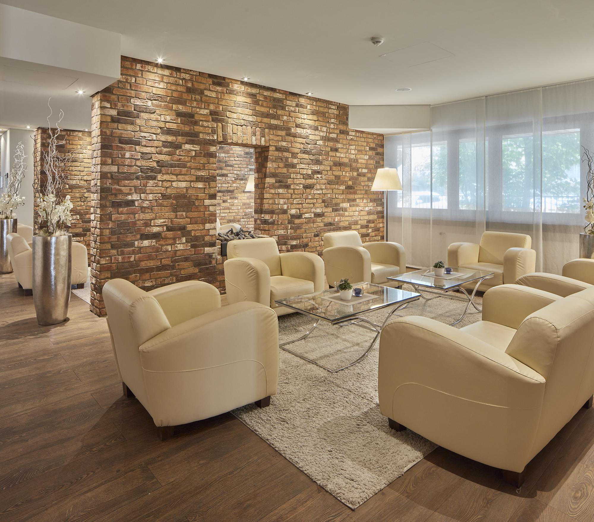 Hell erleuchtete Lounge mit hellen Sofas und Backsteinwänden