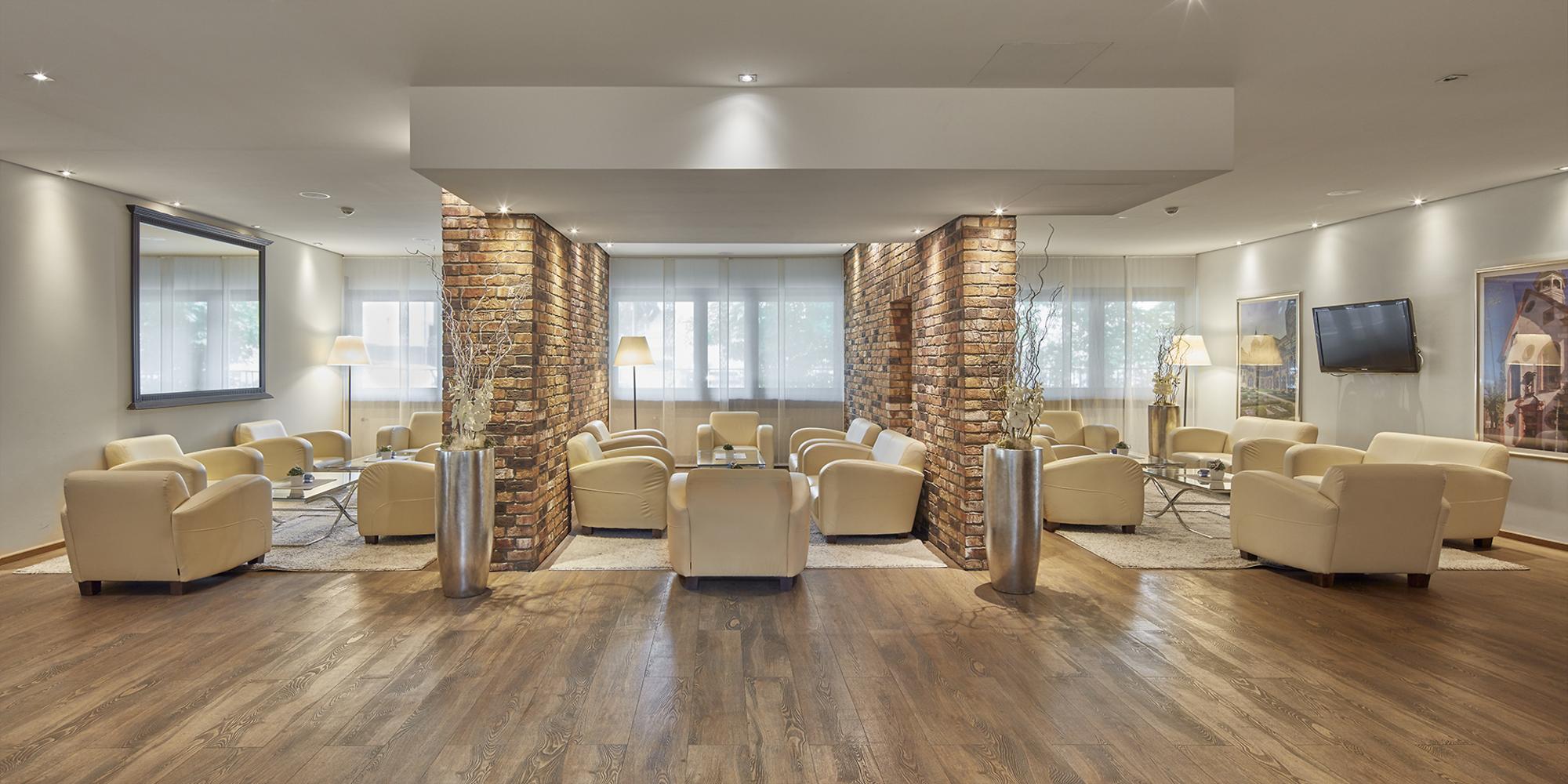 Hell erleuchtete Lounge mit hellen Sofas und Backsteinwänden