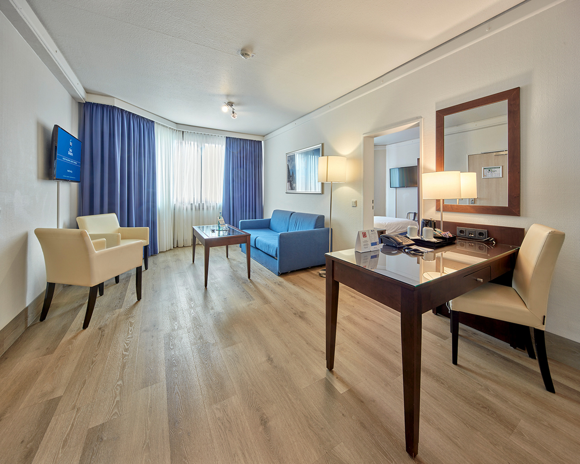 Wohnbereich in der Hotelsuite mit großzügigem Sofa, Couchtisch, zwei Sesseln, TV sowie Schreibtisch